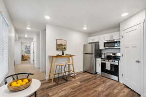 Kitchen featuring stainless steel appliances, white cabinets, light countertops, dark wood finished floors, and recessed lighting