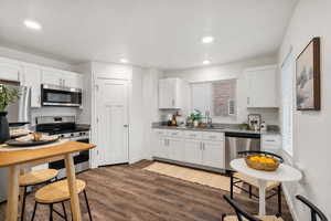 Kitchen featuring stainless steel appliances, white cabinets, dark wood-type flooring, and recessed lighting