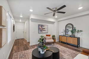 Living area with dark wood-type flooring, a ceiling fan, and recessed lighting