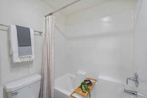 Primary Bathroom with toilet and shower / bath combination with curtain