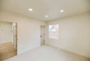 Unfurnished bedroom with light carpet and recessed lighting