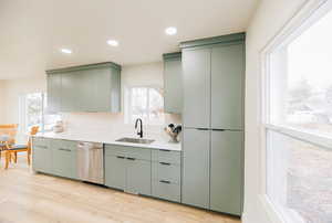 Kitchen with recessed lighting, stainless steel dishwasher, light wood-style flooring, green cabinetry, and light stone countertops