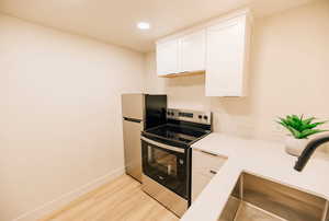 Kitchen featuring appliances with stainless steel finishes, white cabinetry, recessed lighting, and light wood-type flooring