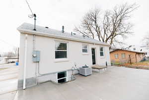 Back of house featuring a patio, brick siding, and roof with shingles