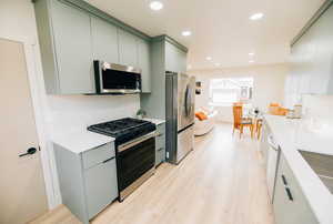 Kitchen featuring stainless steel appliances, recessed lighting, light wood-type flooring, modern cabinets, and green cabinetry