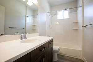 Full bathroom featuring vanity, shower / bathtub combination, dark wood-style floors, and a skylight