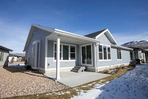 View of snow covered exterior featuring a patio area, a mountain view, and entry steps