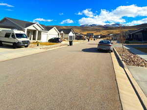 View of asphalt street with a residential view, curbs, sidewalks, and a mountain view