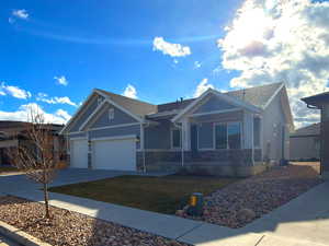 Ranch-style house featuring concrete driveway, stone siding, a front lawn, and a garage