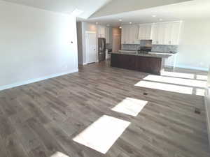 Living area with dark wood-type flooring, vaulted ceiling, ceiling fan, and recessed lighting