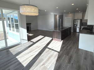 Unfurnished dining area with a fireplace, dark wood finished floors, and a chandelier