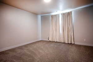 Spare room featuring carpet flooring and baseboards