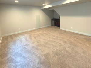 Finished below grade area with light colored carpet and recessed lighting