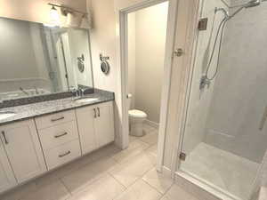 Full bath with a shower stall, double vanity, and light tile patterned floors