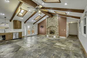 Unfurnished living room featuring french doors, beam ceiling, a brick fireplace, ceiling fan, and stone tile floors