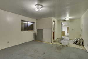 Carpeted spare room with a textured ceiling and baseboards