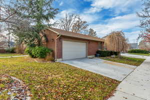 View of home's exterior with brick siding, concrete driveway, a yard, and a garage