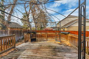 Wooden terrace with a fenced backyard, glass enclosure, and a sunroom