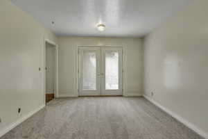 Spare room with light carpet and french doors
