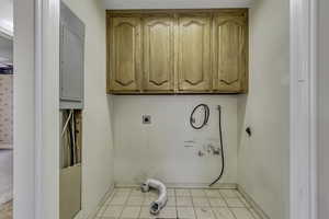 Washroom with electric dryer hookup, cabinet space, electric panel, light tile patterned flooring, and washer hookup