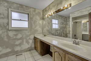 Bathroom with double vanity, a stall shower, wallpapered walls, and light tile patterned flooring
