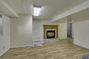 Unfurnished living room featuring a tile fireplace and light wood finished floors