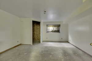 Empty room featuring concrete floors and baseboards