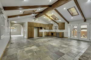 Kitchen with french doors, brown cabinetry, open floor plan, a ceiling fan, and stainless steel dishwasher