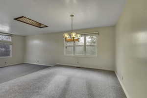 Unfurnished room with carpet, a chandelier, and a skylight