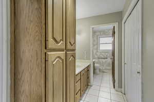 Bathroom with a closet, vanity, and light tile patterned flooring