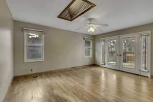Empty room featuring french doors, light wood-type flooring, and a skylight