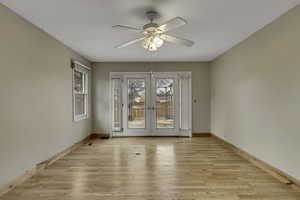 Spare room featuring light wood-type flooring, french doors, and a ceiling fan
