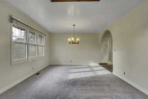 Unfurnished dining area with a chandelier and carpet floors