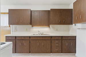Kitchen with light countertops, white range with electric cooktop, brown cabinets, and light tile patterned floors