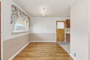 Unfurnished dining area featuring light wood-type flooring and rail lighting