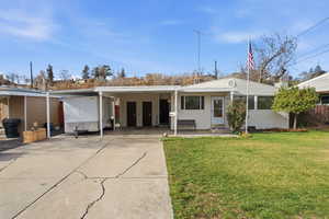 View of front of house featuring a front yard, an attached carport, and driveway