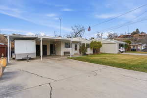 Ranch-style home featuring concrete driveway, a carport, and a front lawn