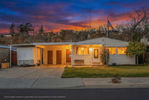 View of front of home with a lawn, a carport, concrete driveway, and covered porch