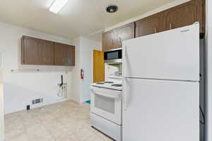 Kitchen with white appliances, light tile patterned flooring, and light countertops