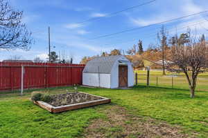 Fenced backyard with a vegetable garden and a storage unit