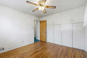 Unfurnished bedroom featuring wood finished floors, a ceiling fan, and a closet