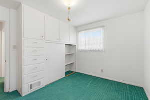 Unfurnished bedroom featuring dark carpet and a closet