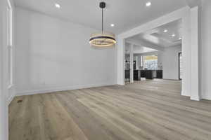Unfurnished dining area featuring light wood-type flooring, recessed lighting, and a chandelier