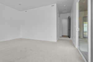 Empty room featuring light colored carpet and baseboards