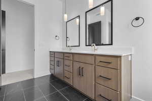 Bathroom featuring double vanity and dark tile patterned floors