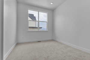 Empty room featuring light colored carpet and baseboards