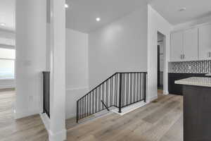 Stairway featuring wood finished floors and recessed lighting