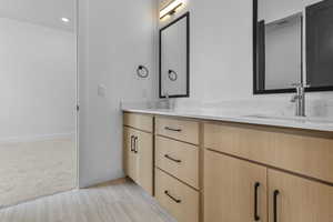 Bathroom with double vanity, light colored carpet, recessed lighting, and light tile patterned floors