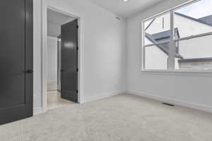 Unfurnished bedroom featuring light carpet and baseboards