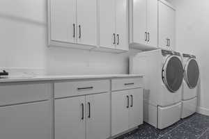 Laundry area with independent washer and dryer, cabinet space, and dark flooring